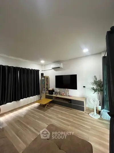 Modern living room with sleek flooring, wall-mounted TV, and stylish decor