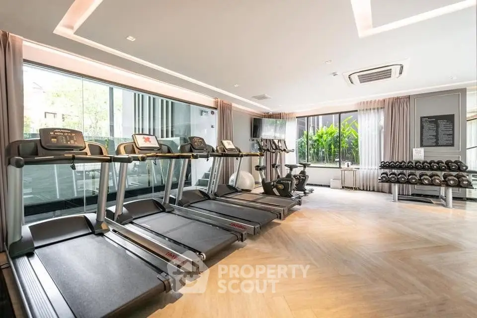 Luxurious gym with modern equipment and large windows in upscale residential building.