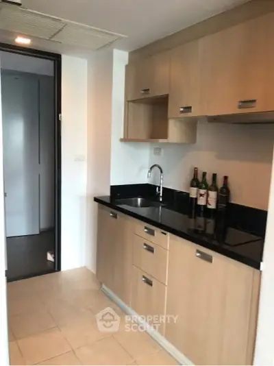 Modern kitchen with sleek cabinets and wine bottles on counter