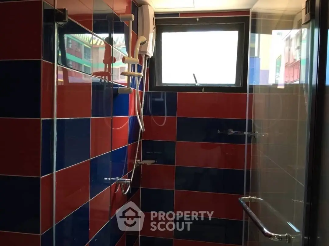 Vibrant bathroom with red and blue tiles and modern shower fixtures.