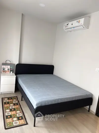 Modern bedroom with sleek bed, air conditioning, and stylish decor in a contemporary apartment.