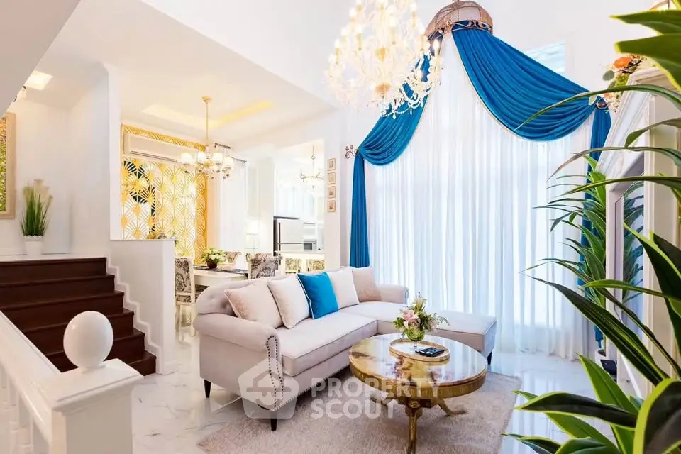 Luxurious living room with elegant decor, plush sofa, and grand chandelier in a bright, airy space.