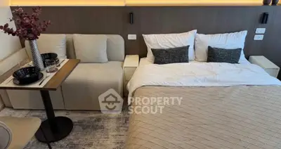 Modern bedroom with cozy bed and stylish dining area in a compact living space.