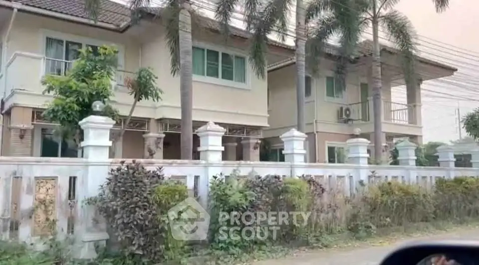 Charming two-story house with lush garden and palm trees, perfect for family living.