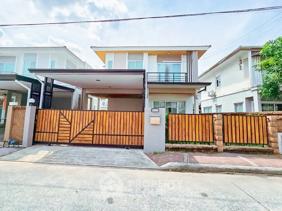Modern two-story house with stylish wooden fence and spacious driveway in a suburban neighborhood.