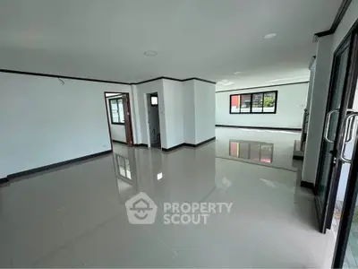 Spacious open-plan living area with glossy tiled floors and large windows for natural light.