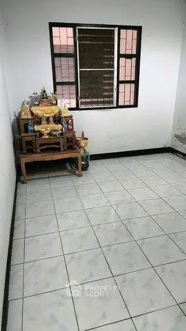 Minimalist room with tiled floor and window, featuring a small altar in the corner.