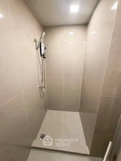Modern minimalist bathroom with sleek tiled shower area and overhead shower fixture.