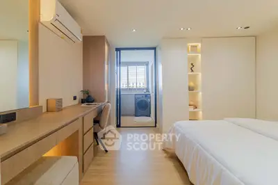 Modern bedroom with built-in desk and view into laundry area, featuring sleek design and ample storage.