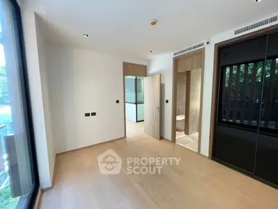 Spacious modern bedroom with wooden flooring and large windows in a luxury apartment.