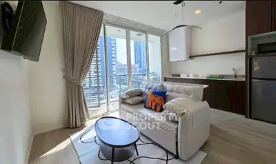 Modern living room with balcony view, sleek kitchen, and stylish decor in urban apartment.