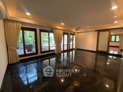 Spacious living room with marble flooring and large windows overlooking garden
