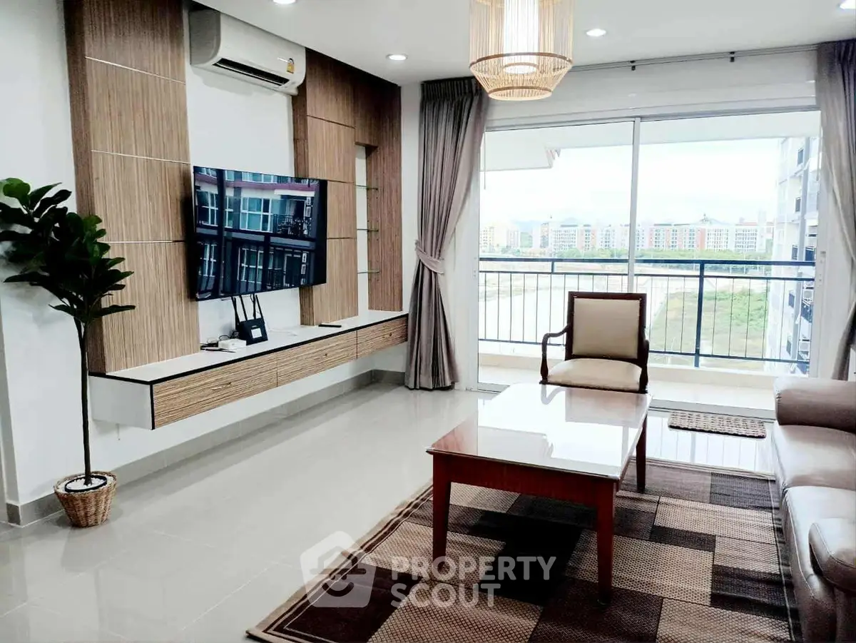Modern living room with large TV, balcony view, and stylish furniture