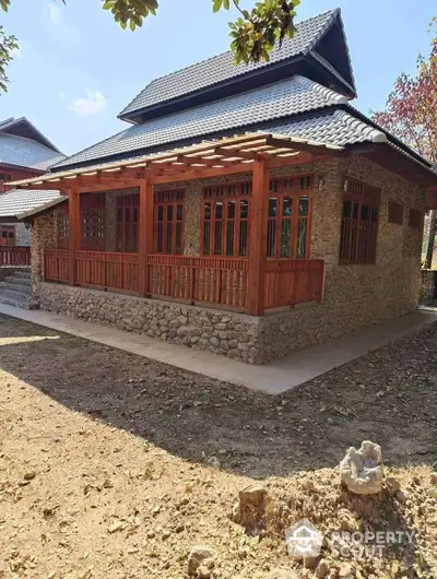 Charming rustic stone house with wooden accents and spacious porch in serene natural setting.