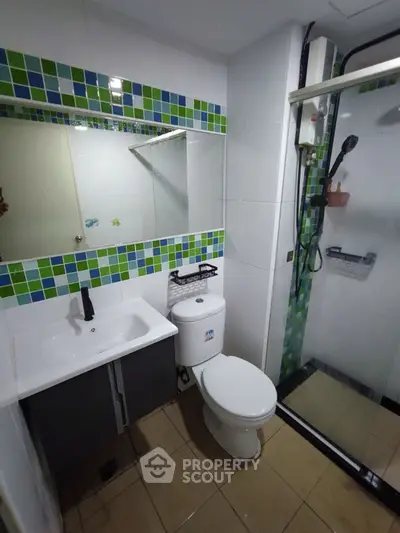 Modern bathroom with shower and colorful tile accents.