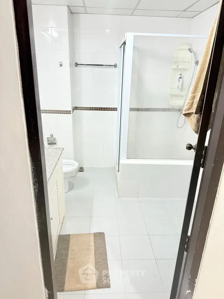 Spacious bathroom with modern shower and sleek white tiles, perfect for a contemporary home.