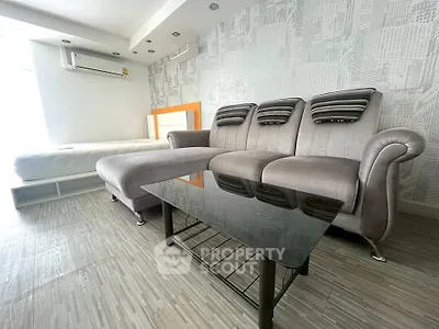 Modern living room with stylish gray sofa and glass coffee table, featuring sleek flooring and contemporary decor.