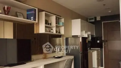 Modern kitchen with sleek cabinetry and stainless steel appliances in a cozy apartment setting.