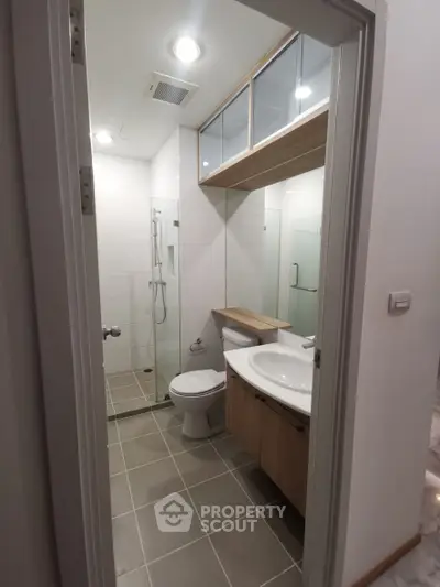 Modern bathroom with glass shower and sleek vanity in contemporary apartment.