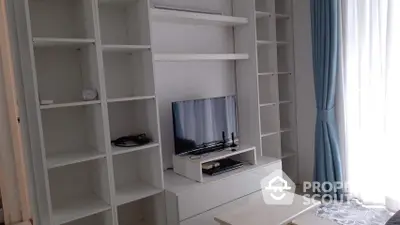 Spacious living room with custom white shelving units and modern entertainment setup, complemented by elegant blue curtains.