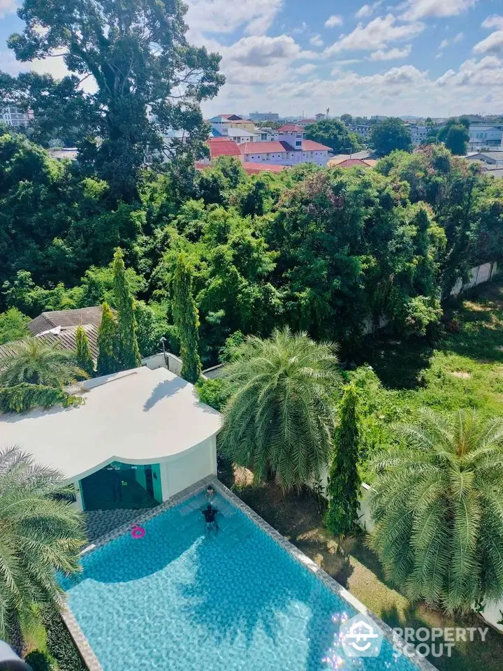 Stunning aerial view of luxurious pool surrounded by lush greenery and modern architecture.