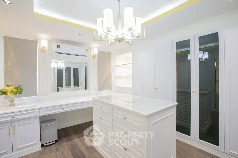 Luxurious walk-in closet with elegant white cabinetry and modern lighting