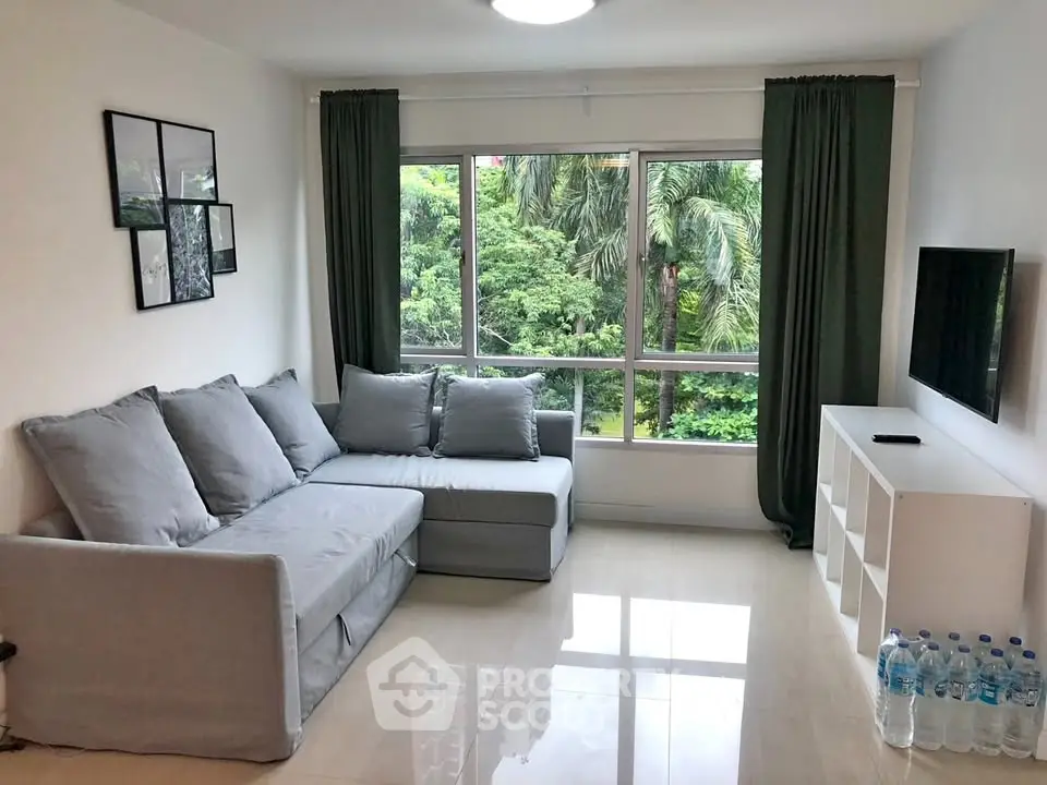 Modern living room with large windows and lush greenery view