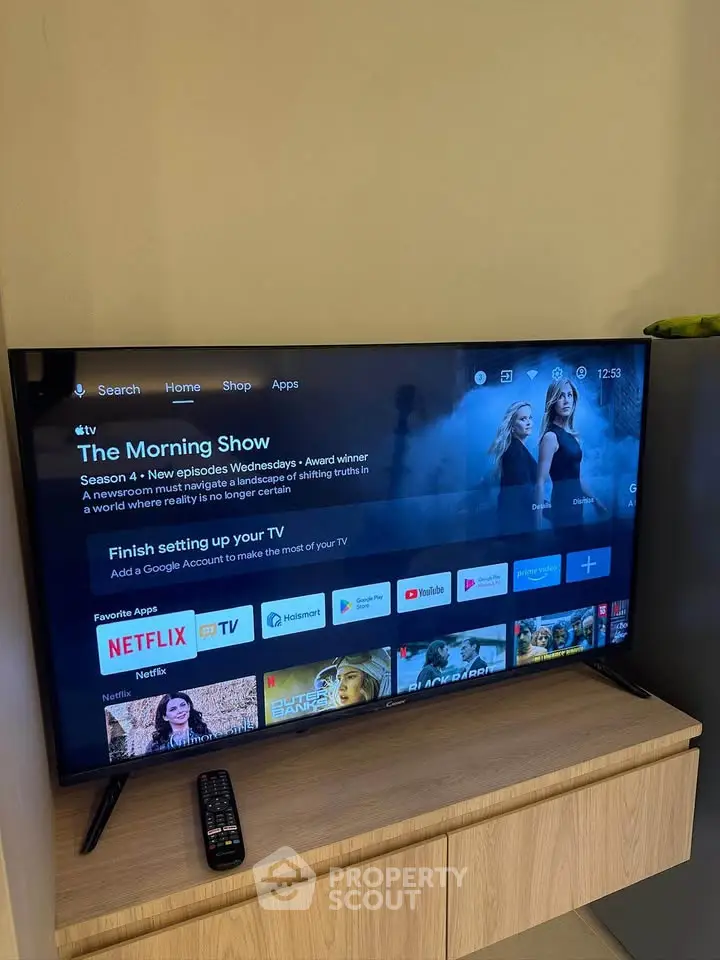 Modern living room with sleek TV setup on wooden stand, showcasing streaming apps and entertainment options.