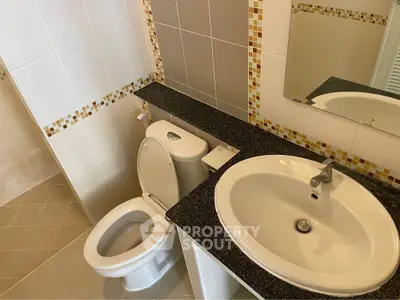Compact and clean bathroom with white fixtures, mirror, and neutral tile work, ideal for modern living.
