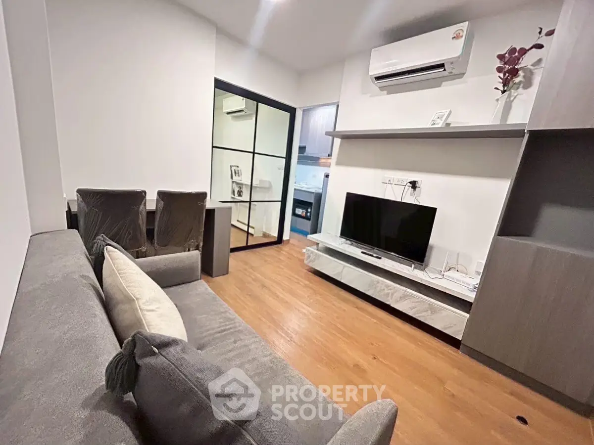 Modern living room with sleek design, featuring a cozy sofa, wall-mounted TV, and air conditioning unit.
