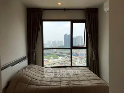 Cozy bedroom with city view from large window, perfect for urban living.