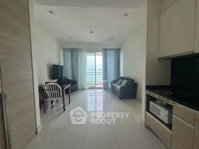 Spacious living room with ocean view, modern furniture, and sleek kitchen area.