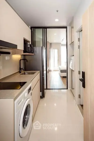 Modern kitchen with sleek appliances and open layout leading to a bright bedroom.