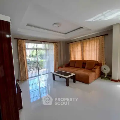 Spacious living room with large windows and elegant curtains, featuring a comfortable sofa and coffee table.