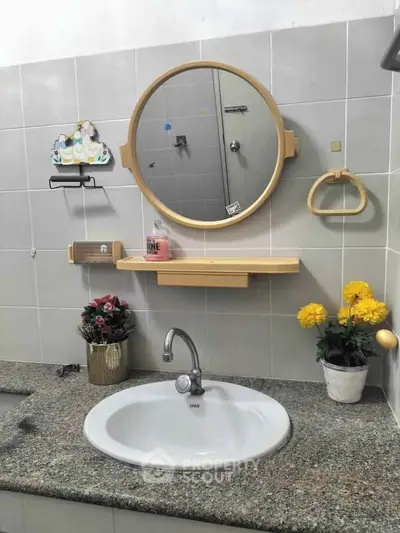 Charming bathroom with round mirror, elegant fixtures, and decorative plants for a cozy ambiance.
