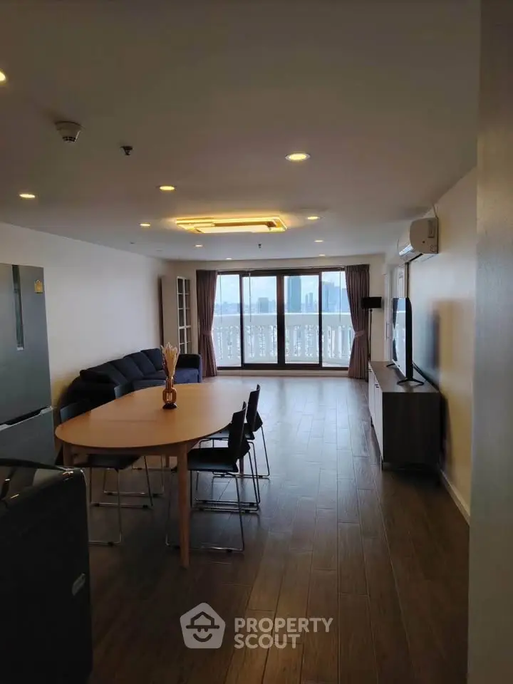 Spacious living room with modern furniture and stunning city view through large windows.