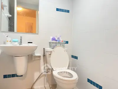 Modern bathroom with white tiles and sleek fixtures, featuring a toilet and sink.