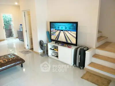 Spacious and well-lit living room with modern amenities, featuring a large flat-screen TV, comfortable seating, and sleek storage solutions, perfect for family gatherings and entertainment.