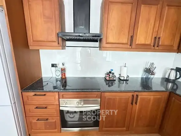 Elegant kitchen with wooden cabinets and modern appliances, featuring a sleek oven and granite countertops.