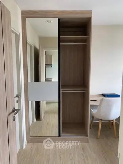 Modern bedroom with built-in wardrobe and study desk, featuring sleek wood finishes.