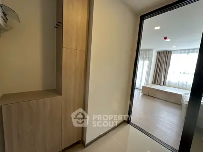 Modern apartment interior with sleek wooden storage and spacious bedroom view.