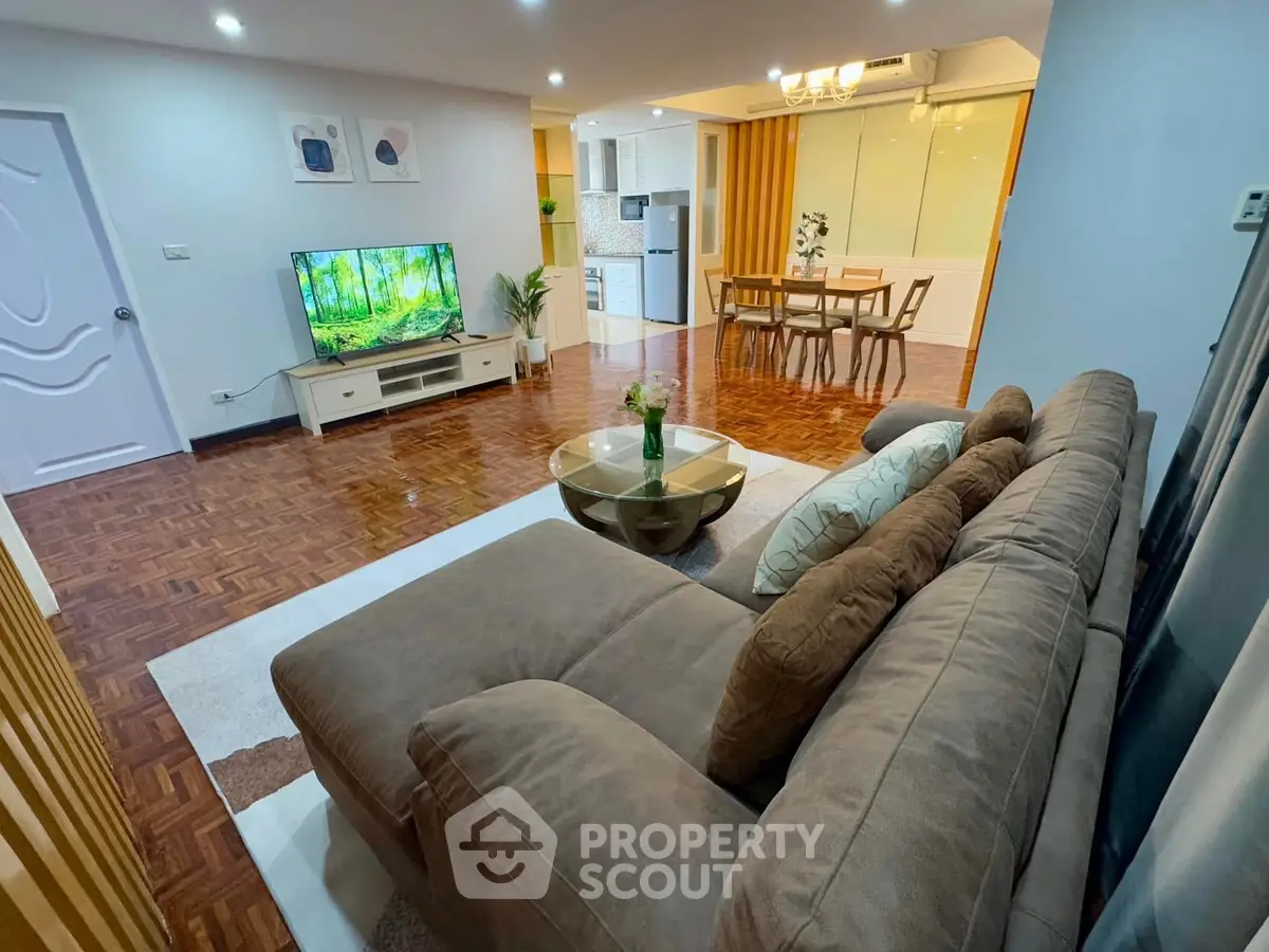 Spacious modern living room with cozy sofa and open dining area, perfect for entertaining.