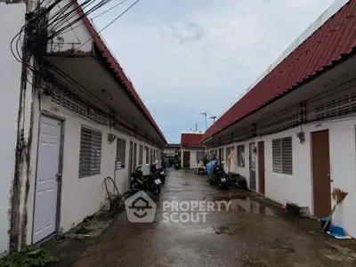 Charming row of single-story units with red roofs and a communal walkway, ideal for cozy living.