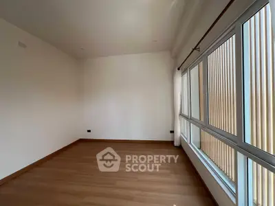 Spacious empty room with large windows and wooden flooring, perfect for customization.