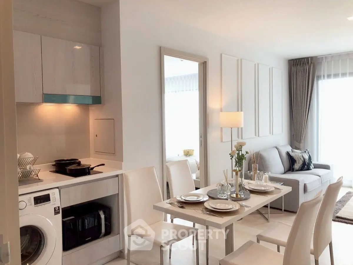 Modern open-plan living room with dining area and kitchen, featuring sleek furniture and natural light.