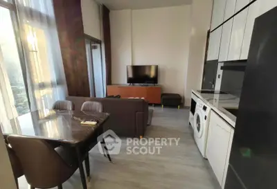 Modern living room with open kitchen, featuring sleek furniture and large windows for natural light.