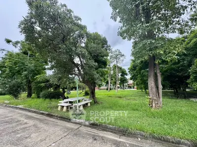 Serene green park with lush trees and a picnic table, perfect for relaxation.