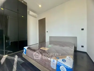 Modern bedroom with sleek black wardrobe and new mattress in stylish apartment.