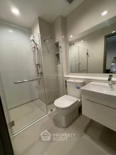Modern bathroom with glass shower enclosure and sleek fixtures in a contemporary apartment.