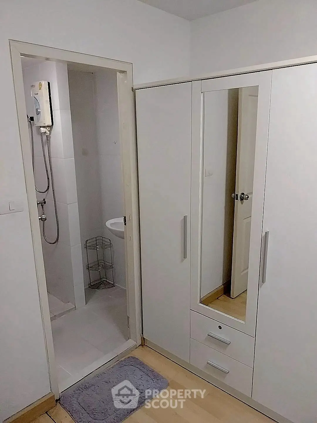 Compact bathroom with shower and adjacent wardrobe in modern apartment.